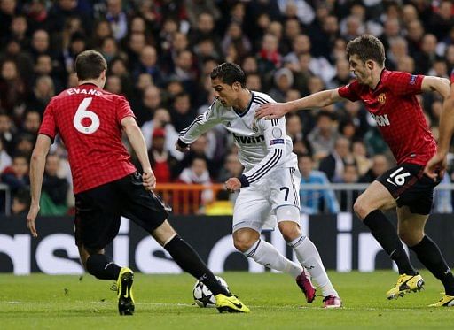 Real Madrid's Cristiano Ronaldo (C) vies with Manchester United's Michael Carrick (R) in Madrid on February 13, 2013